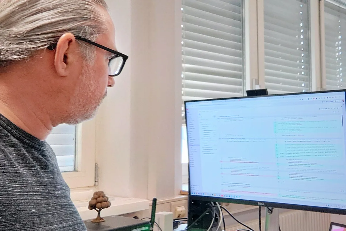 Arthur Zaczek, Geschäftsführer von DevCircle, im Profil an seinem Arbeitsplatz vor einem Bildschirm mit Programmcode